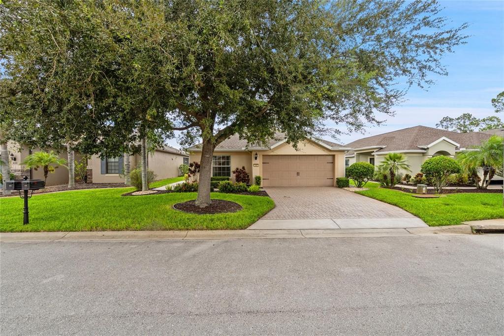 A single-story house with a tan exterior, a paved driveway, and a large front tree — 418 DEL SOL AVENUE, DAVENPORT, FL