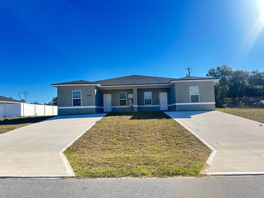A single-story duplex features gray stucco siding, two front doors, and two concrete driveways — 15885 SW 35TH COURT ROAD UNIT 1, OCALA, FL