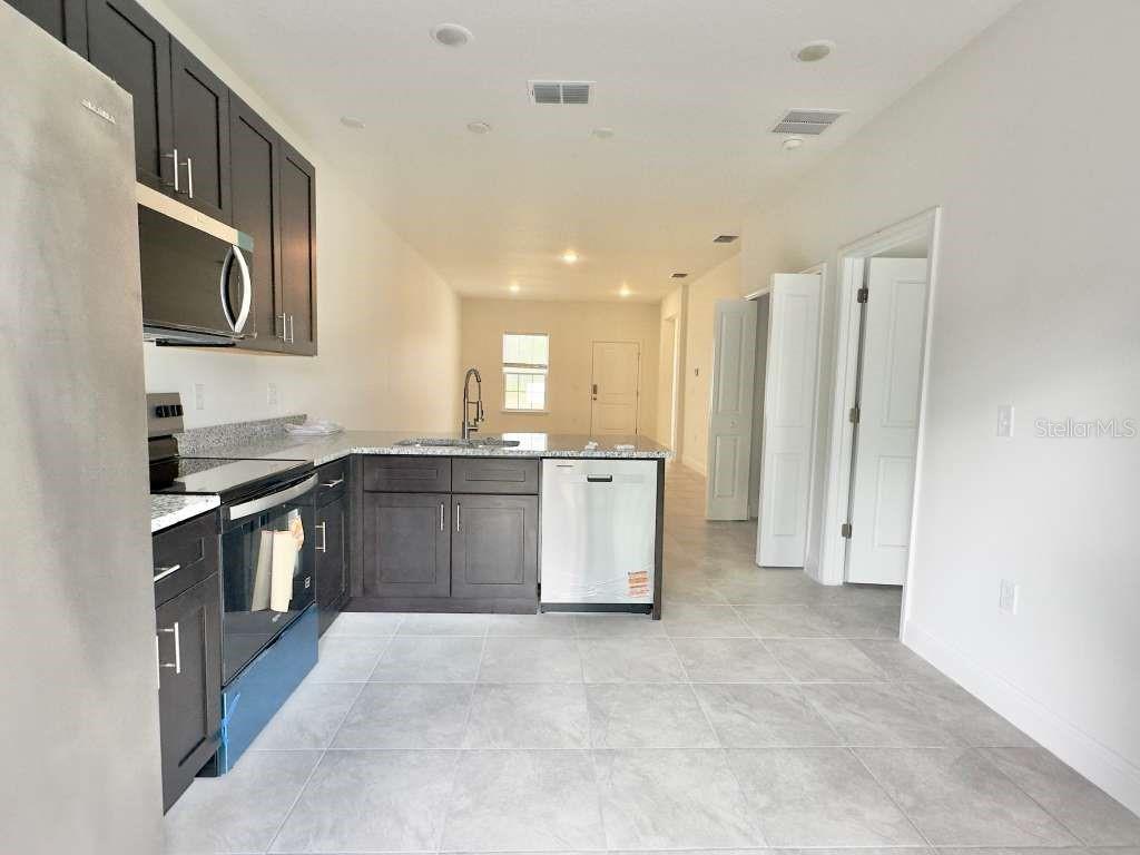 A kitchen with dark cabinets, stainless steel appliances, and light tile flooring — 15885 SW 35TH COURT ROAD UNIT 1, OCALA, FL