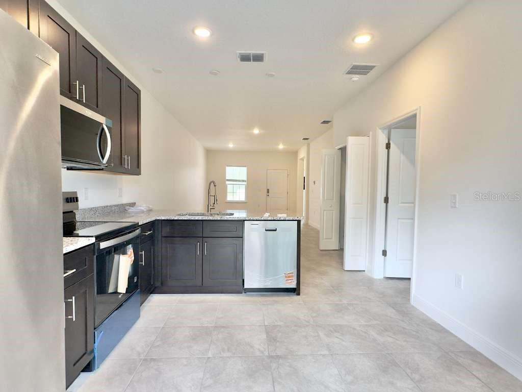 A kitchen with dark cabinets, stainless steel appliances, and light tile flooring — 15885 SW 35TH COURT ROAD UNIT 1, OCALA, FL