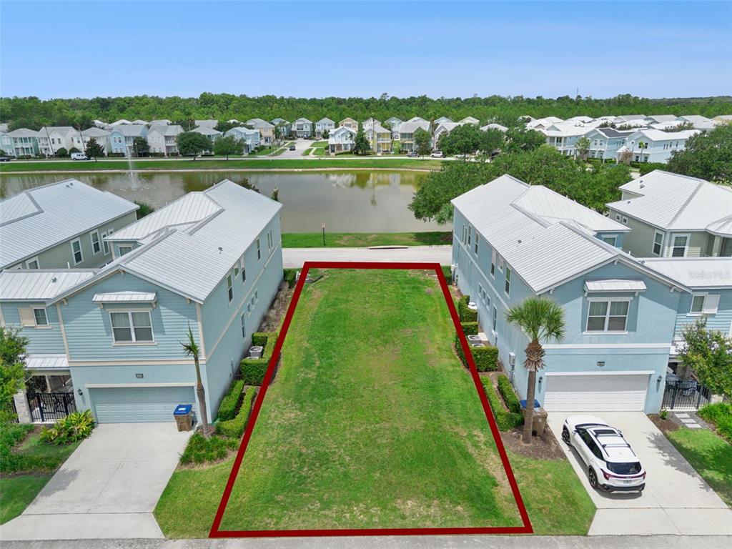 An aerial view shows a vacant residential lot situated between two light blue houses — 1513 FAIRVIEW CIRCLE, REUNION, FL