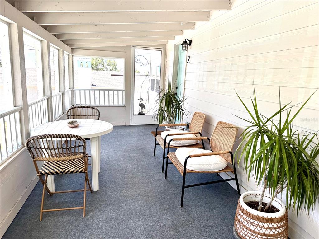 A covered porch features a round table, three wicker chairs, and two potted plants — 1357 LAKESHORE DRIVE UNIT 3, MOUNT DORA, FL