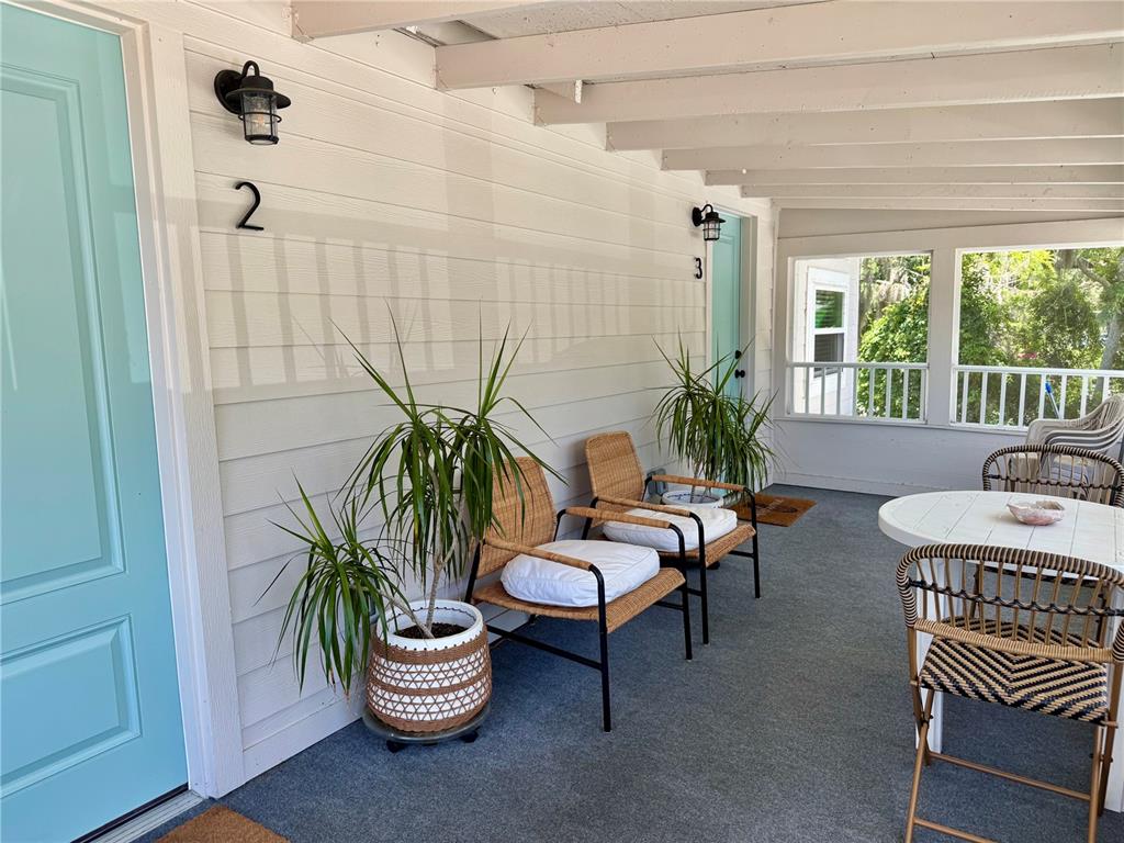 A covered porch features two light blue doors, wicker chairs, and a small round table — 1357 LAKESHORE DRIVE UNIT 3, MOUNT DORA, FL