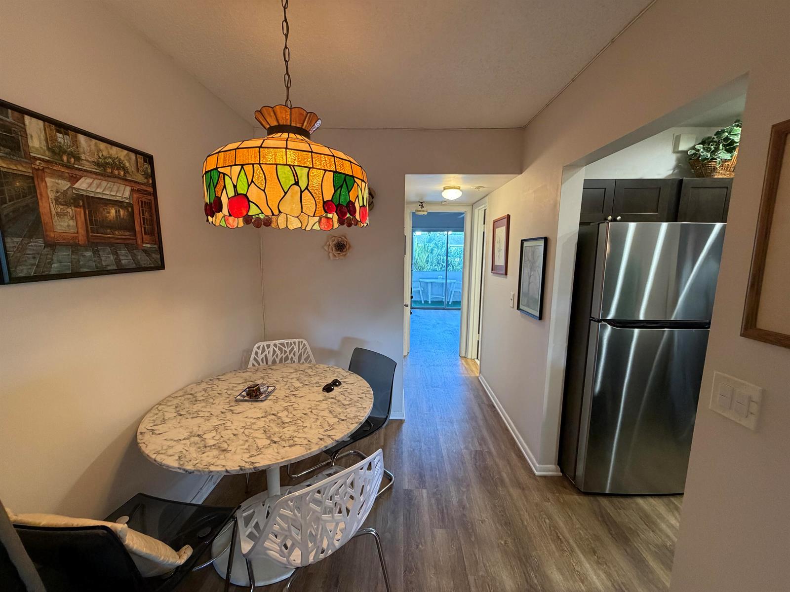 A dining area with a marble-topped table and stained-glass pendant light leads to a kitchen — 107 Prescott E, Deerfield Beach FL 33442, DEERFIELD BEACH, FL