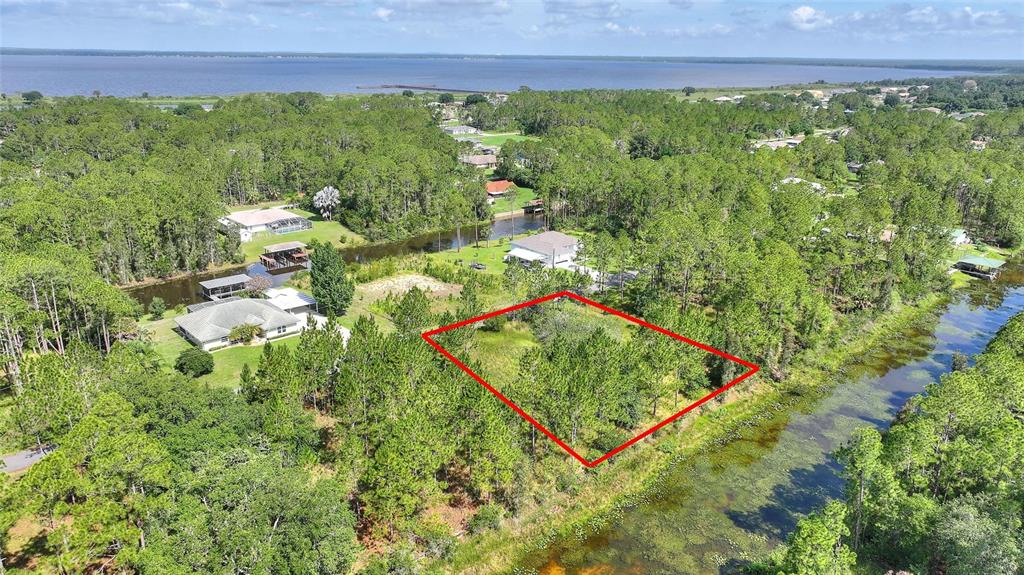 An aerial view shows a vacant, tree-covered lot outlined in red near a canal — 26 LANTANA DRIVE S, INDIAN LAKE ESTATES, FL