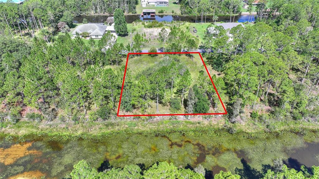An aerial view shows a rectangular, wooded vacant lot outlined in red next to a canal — 26 LANTANA DRIVE S, INDIAN LAKE ESTATES, FL