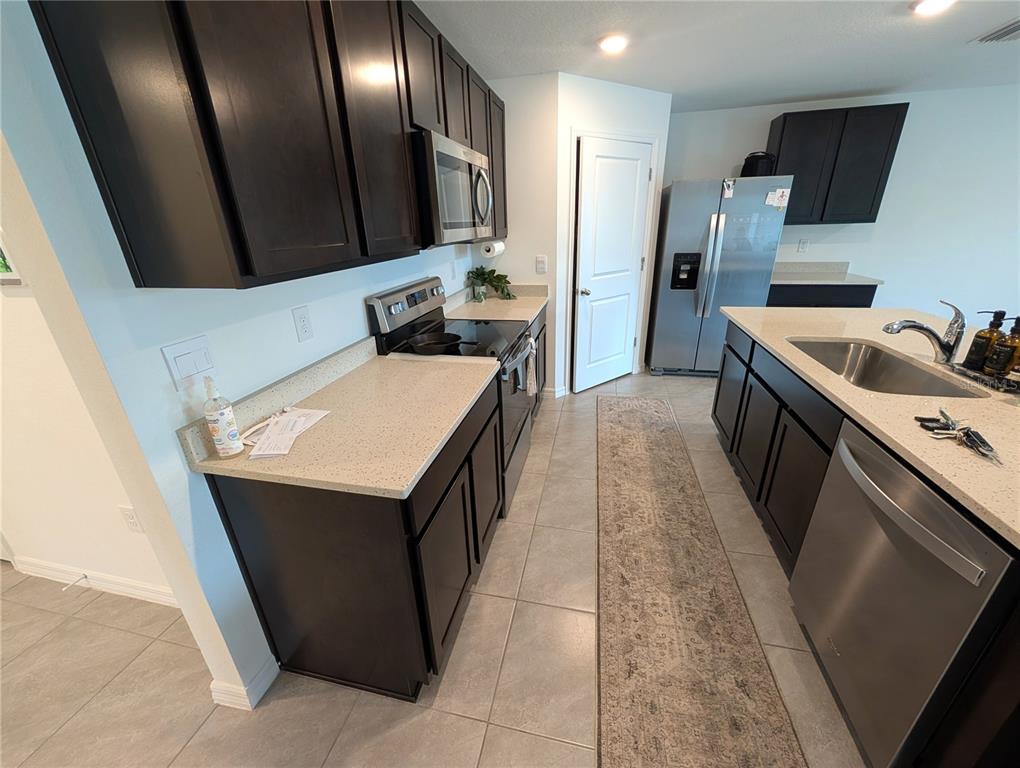 A kitchen features dark cabinets, stainless steel appliances, light countertops, and a central island — 801 ACE OUTLAW AVENUE, RUSKIN, FL