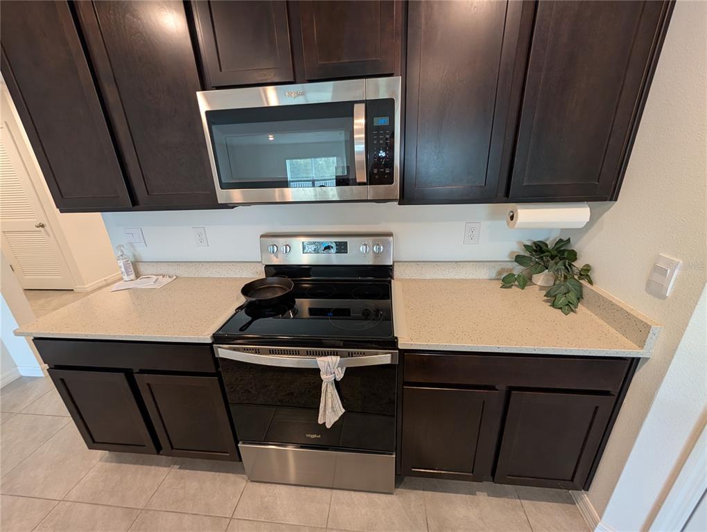 A kitchen features dark wood cabinets, stainless steel appliances, and light-colored speckled countertops — 801 ACE OUTLAW AVENUE, RUSKIN, FL