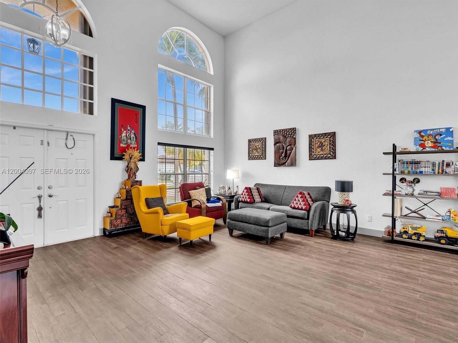 A living room with high ceilings, large arched windows, and wood-look flooring — 17351 SW 32nd Ct, Miramar FL 33029, MIRAMAR, FL