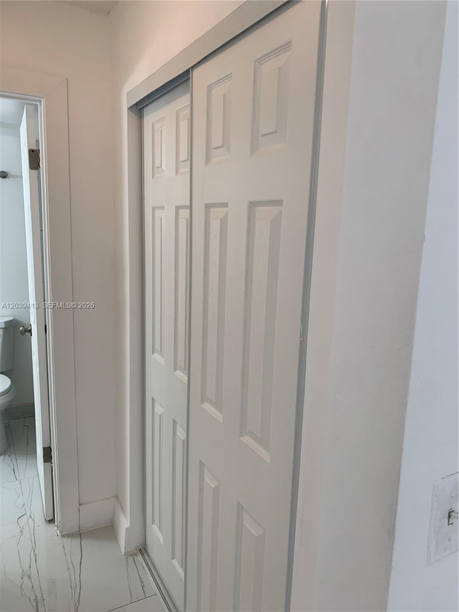 A white sliding closet door is positioned next to a doorway leading into a bathroom — NORTH MIAMI, FL