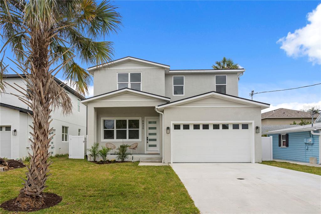 A two-story light gray house features a front porch, a two-car garage, and a palm tree — 6830 S DE SOTO STREET, TAMPA, FL