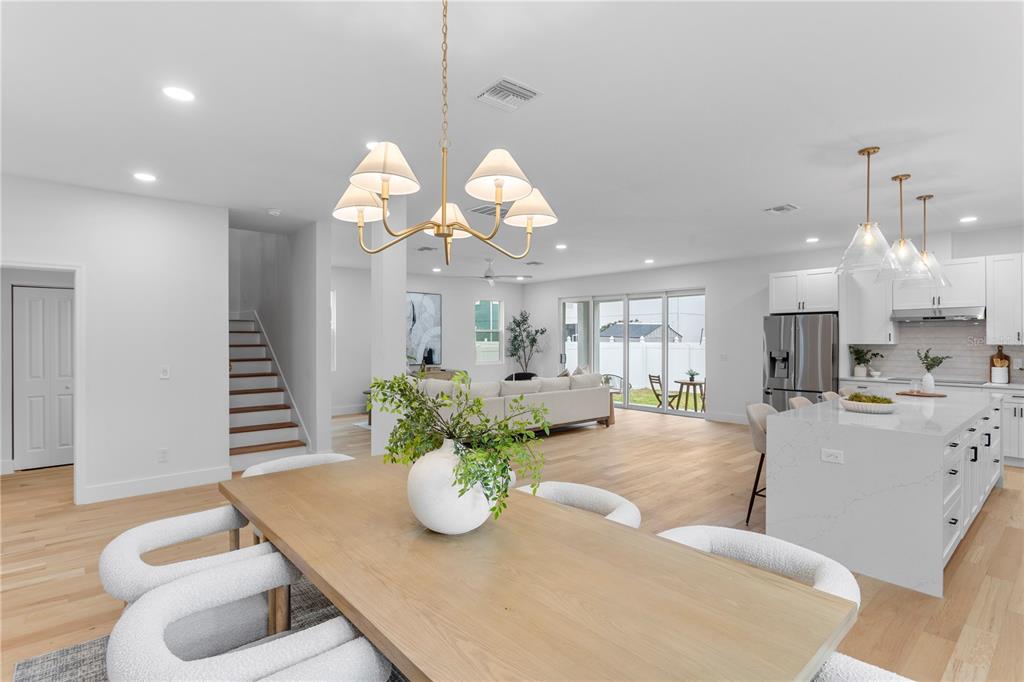 An open-concept dining area and kitchen feature light wood floors, white cabinetry, and modern lighting — 6830 S DE SOTO STREET, TAMPA, FL