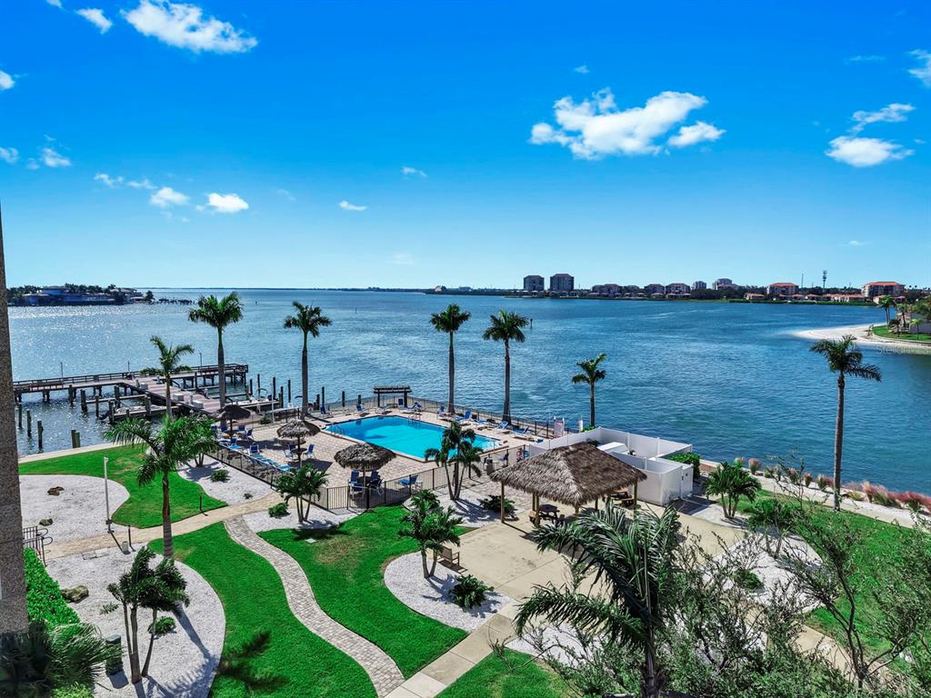 An elevated view of a waterfront swimming pool, palm trees, and a wooden boat dock — 5220 BRITTANY DRIVE S UNIT 603, ST PETERSBURG, FL