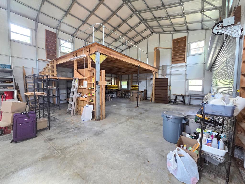 A large, open-concept metal warehouse space features a wooden loft, concrete floors, and roll-up doors — 6504 WERNER AVENUE, NEW PORT RICHEY, FL