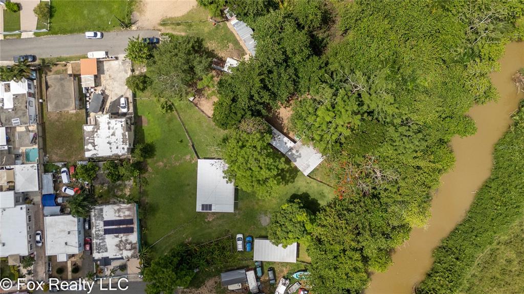 An aerial view shows a residential property with multiple buildings, green lawns, and a river — BO ESPINAL, AGUADA, PR