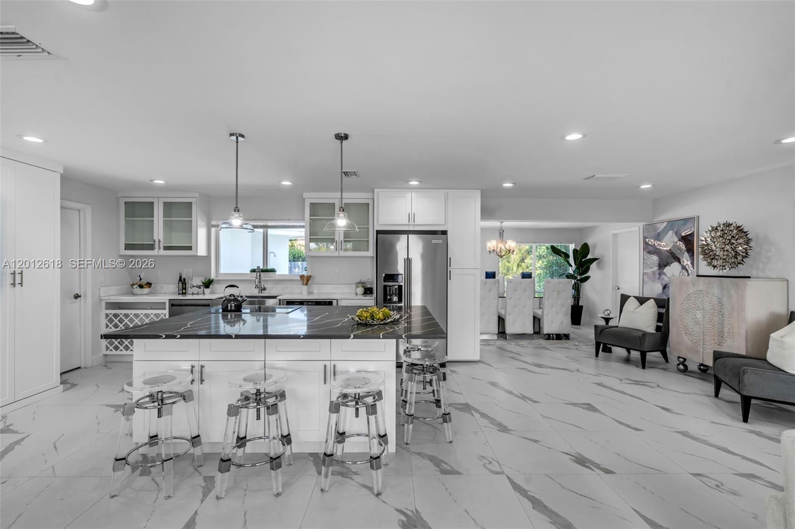 A modern kitchen features a large black marble island, white cabinetry, and light tile flooring — 465 NW 11th St, Boca Raton FL 33432, BOCA RATON, FL