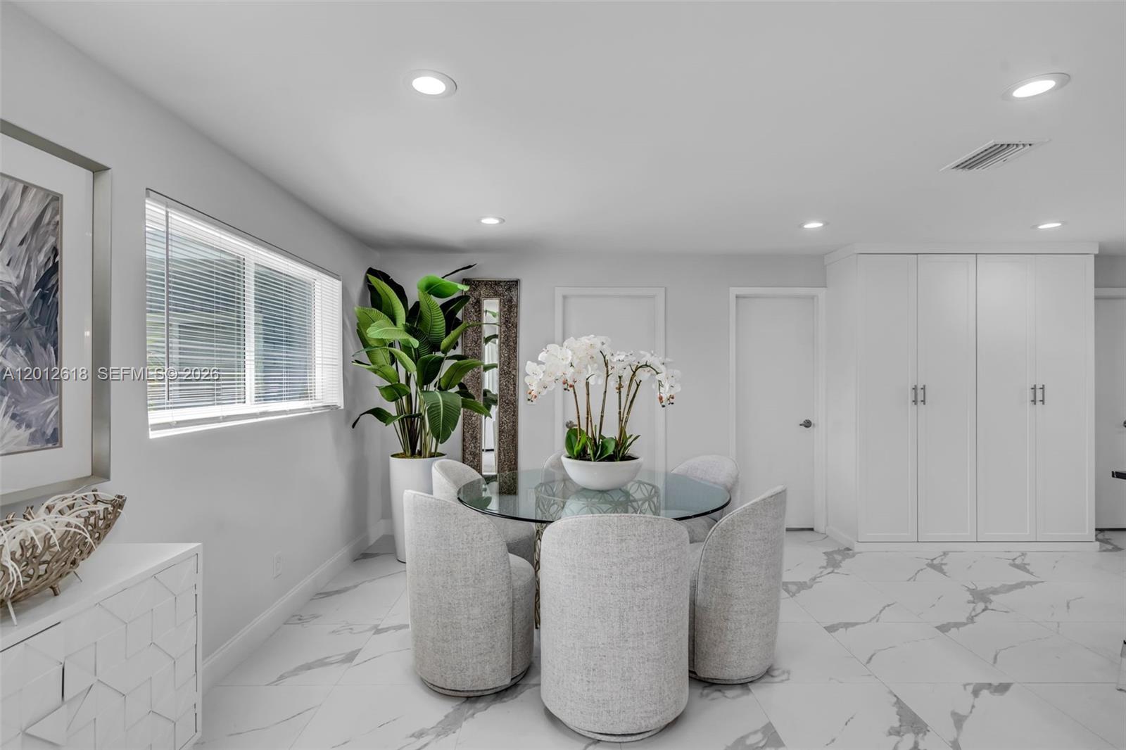 A dining room features a glass table, four upholstered chairs, a large plant, and white cabinetry — 465 NW 11th St, Boca Raton FL 33432, BOCA RATON, FL