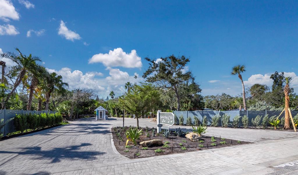 A paved driveway leads to the gated entrance of a community with lush landscaping — 7219 PINE NEEDLE ROAD, SARASOTA, FL