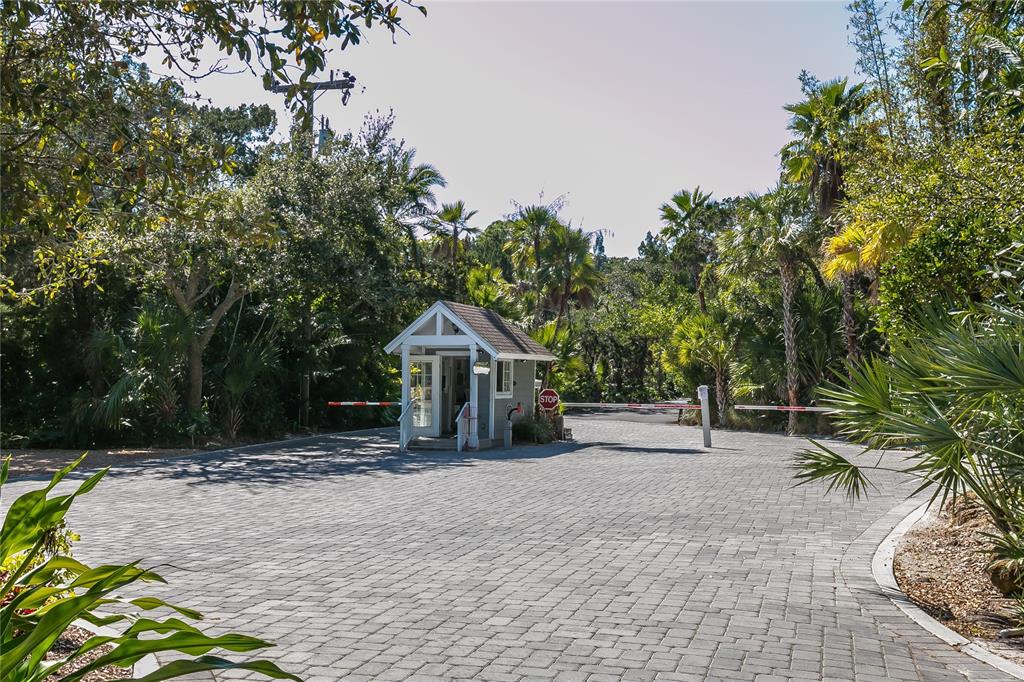 A small guard house stands at the entrance of a paved gated community driveway — 7219 PINE NEEDLE ROAD, SARASOTA, FL