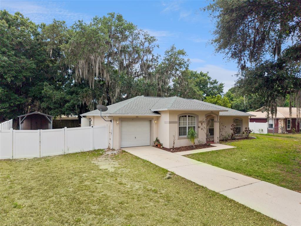 A single-story house with a white garage door, beige siding, and a white vinyl fence — 305 E 5TH STREET, ST CLOUD, FL