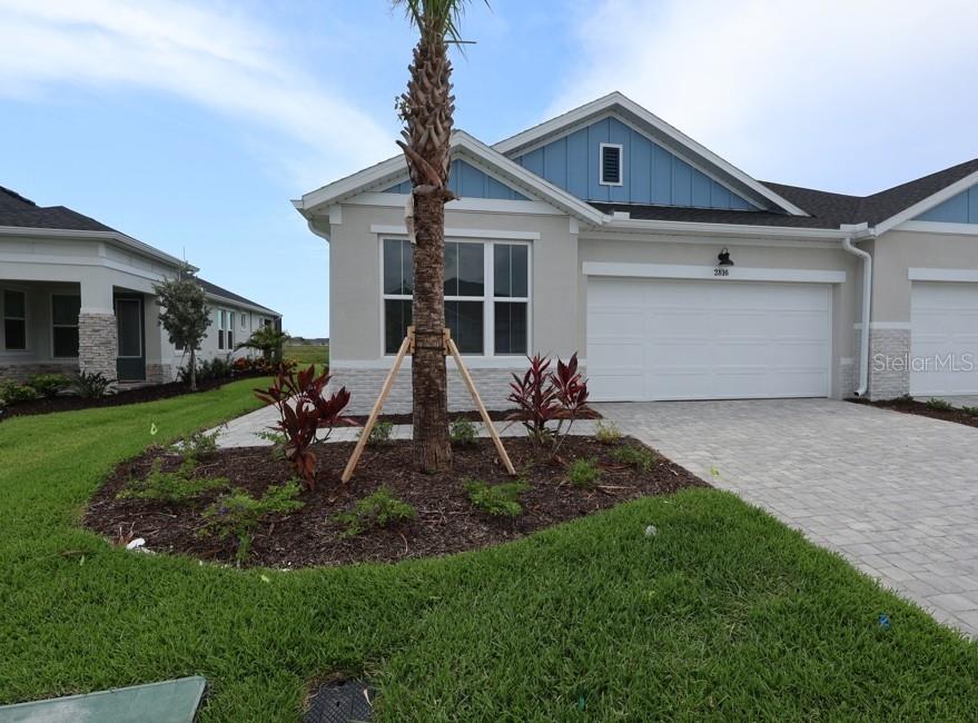 A single-story house exterior features a white garage, blue gable siding, and a palm tree — 2816 MARRAKESH LANE, SARASOTA, FL