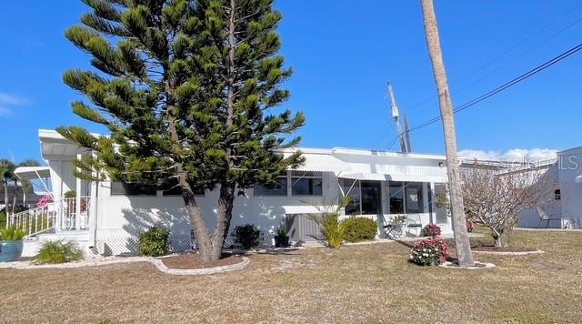 A white mobile home with a large pine tree in the front yard — 740 CAREFREE, VENICE, FL