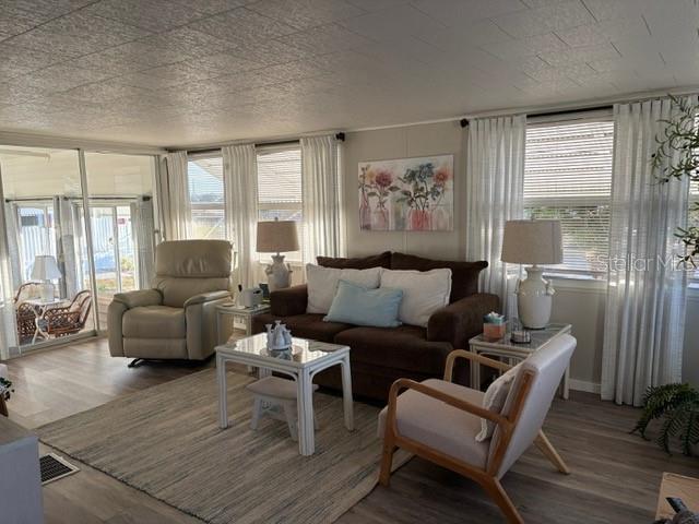 A living room features a brown sofa, a recliner, a light-colored armchair, and large windows — 740 CAREFREE, VENICE, FL