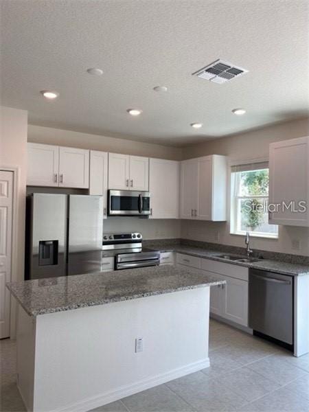 A kitchen features white cabinets, granite countertops, stainless steel appliances, and a central island — 4306 SAILPLANE COURT, WESLEY CHAPEL, FL