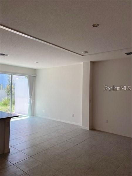 An open-concept room features light-colored tile flooring, white walls, and a sliding glass door — 4306 SAILPLANE COURT, WESLEY CHAPEL, FL