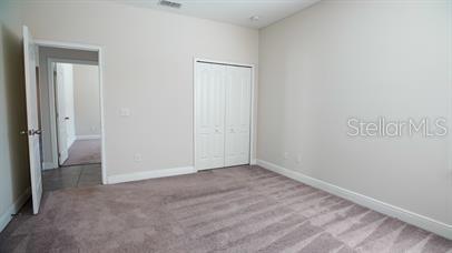 A bedroom with beige walls, carpeted flooring, and a white closet with double doors — 161 KENNY BOULEVARD, HAINES CITY, FL