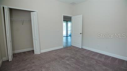 A bedroom features beige walls, gray carpet, a closet with bifold doors, and an open doorway — 161 KENNY BOULEVARD, HAINES CITY, FL