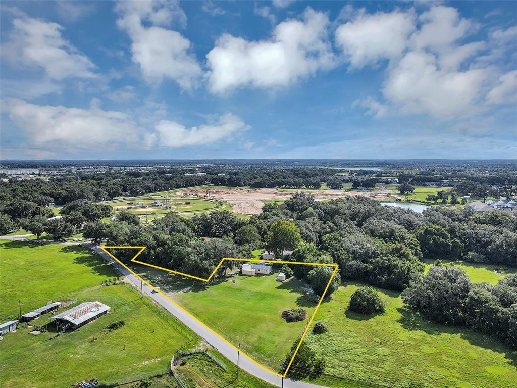 An aerial view shows a rural property with a house and outbuildings outlined in yellow — 510 PHILLIPS LANE, WILDWOOD, FL