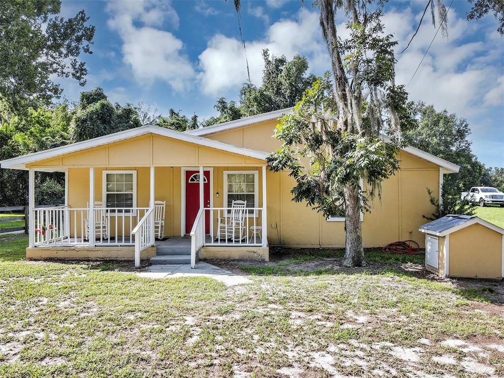 A yellow single-story house with a front porch and a small shed in the yard — 510 PHILLIPS LANE, WILDWOOD, FL