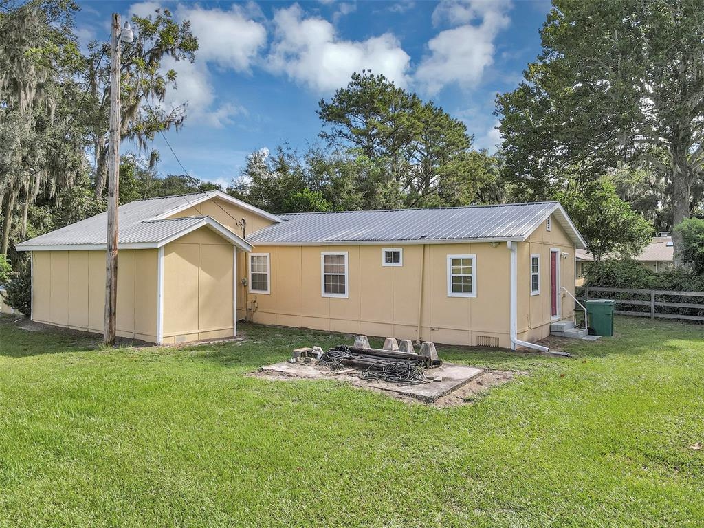 The exterior of a yellow, single-story house with a metal roof and a concrete pad — 510 PHILLIPS LANE, WILDWOOD, FL