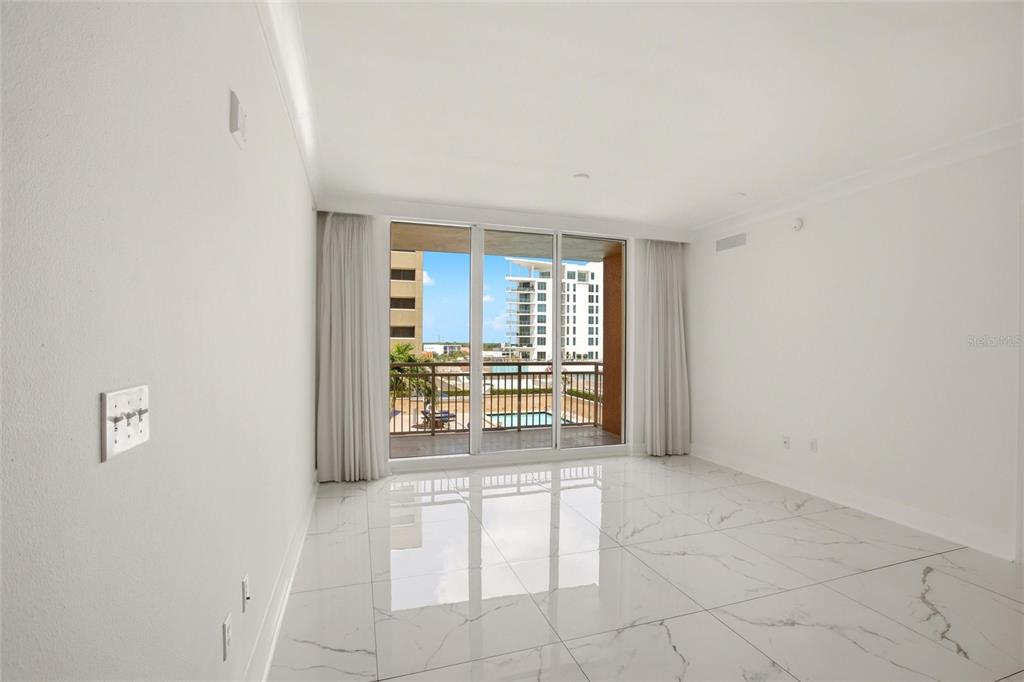 A bright, empty room features white marble-look tile flooring, white walls, and floor-to-ceiling windows — 1350 MAIN STREET UNIT 707, SARASOTA, FL