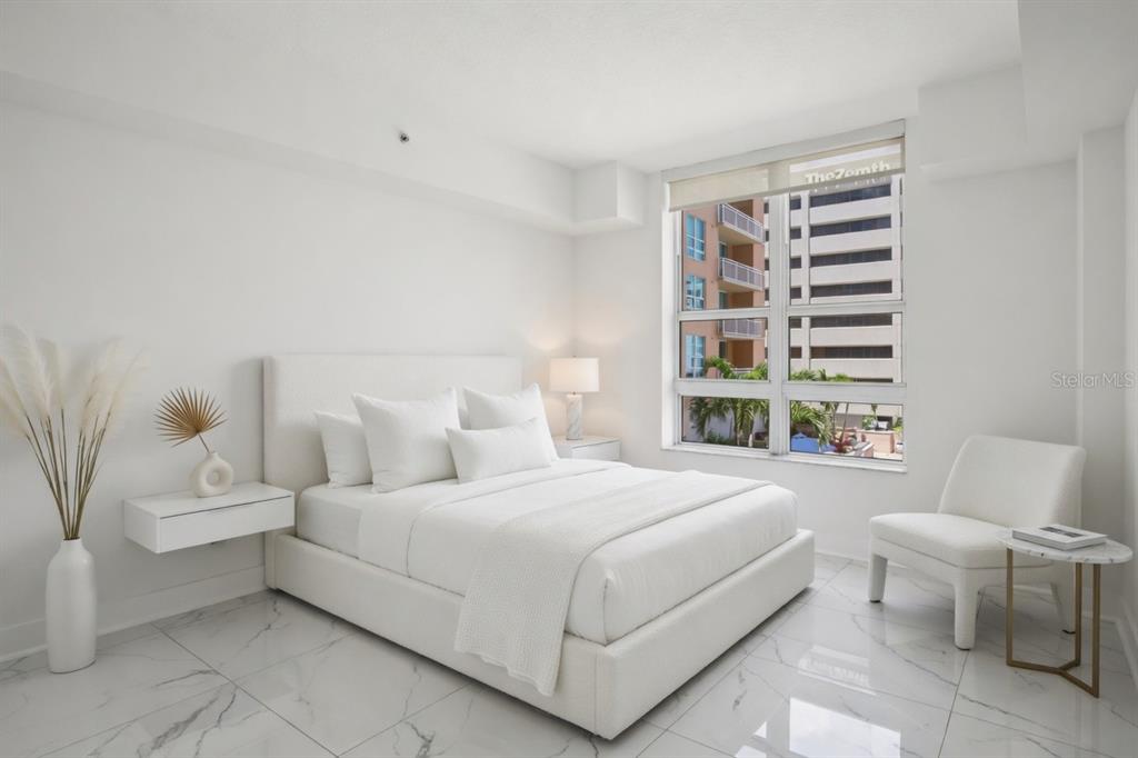 A modern bedroom features a white bed, marble-style tile flooring, and a large window — 1350 MAIN STREET UNIT 707, SARASOTA, FL