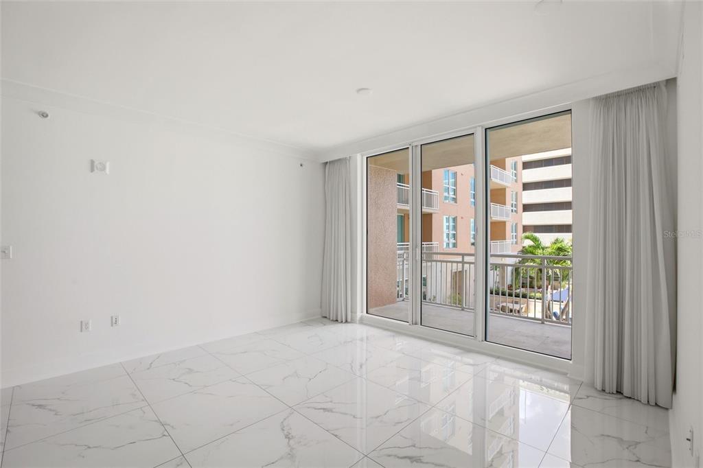 An empty room with white marble-look tile flooring and sliding glass doors leading to a balcony — 1350 MAIN STREET UNIT 707, SARASOTA, FL