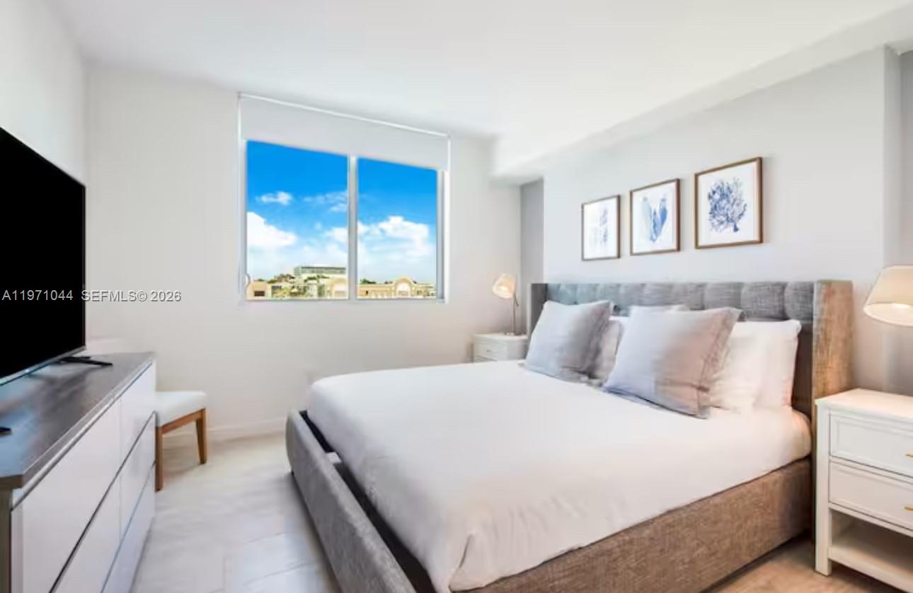 A bedroom features a gray upholstered bed, white nightstands, and a large window with views — 3900 Biscayne Blvd # 402, Miami FL 33137, MIAMI, FL