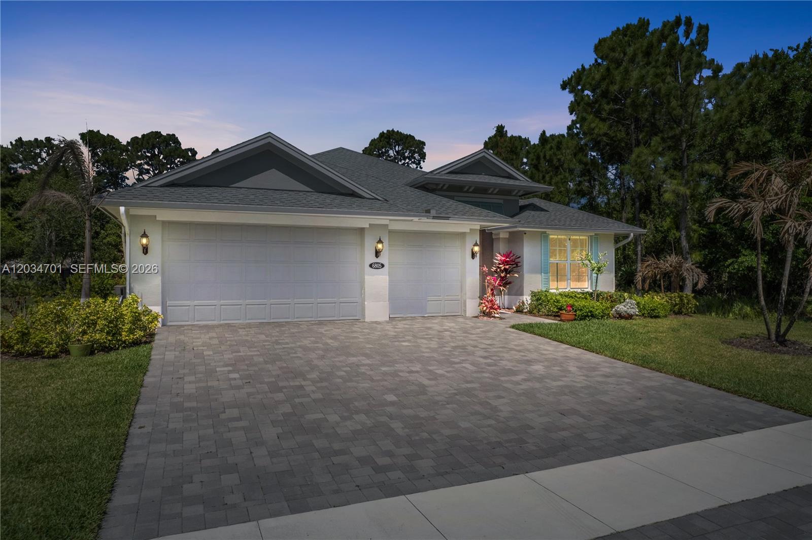 A single-story house with a three-car garage and a paved driveway at dusk — 6805 49th Ct, Vero Beach FL 32967, VERO BEACH, FL