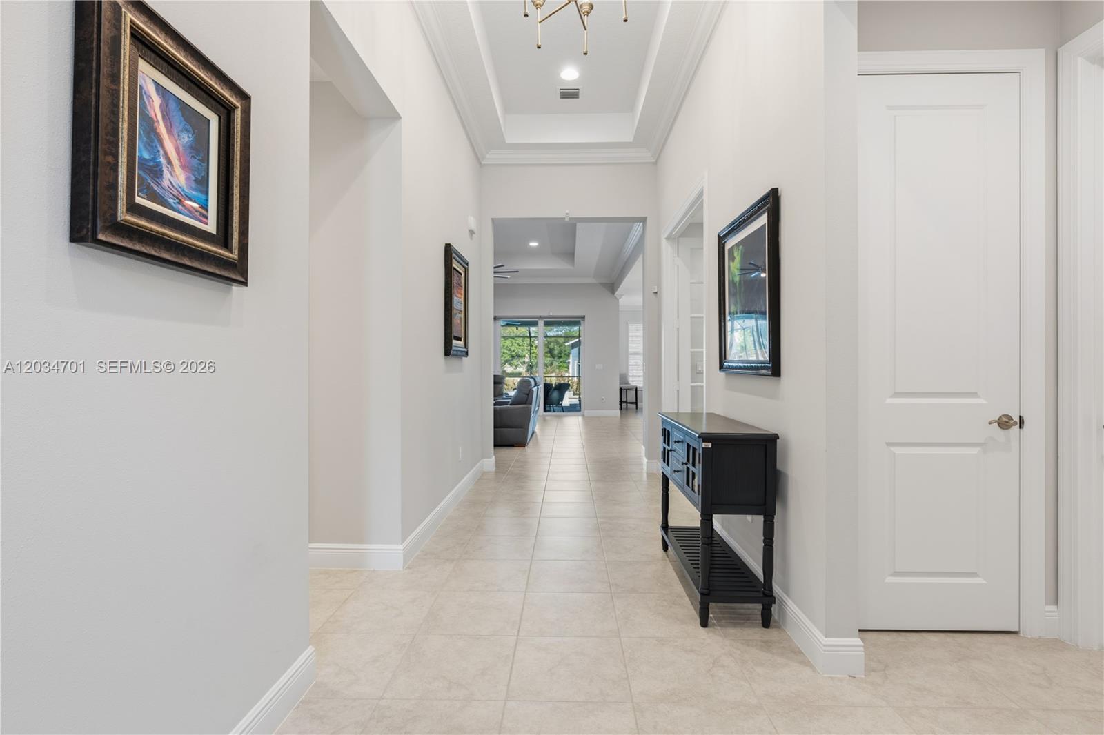 A tiled hallway leads to an open living area with a tray ceiling — 6805 49th Ct, Vero Beach FL 32967, VERO BEACH, FL