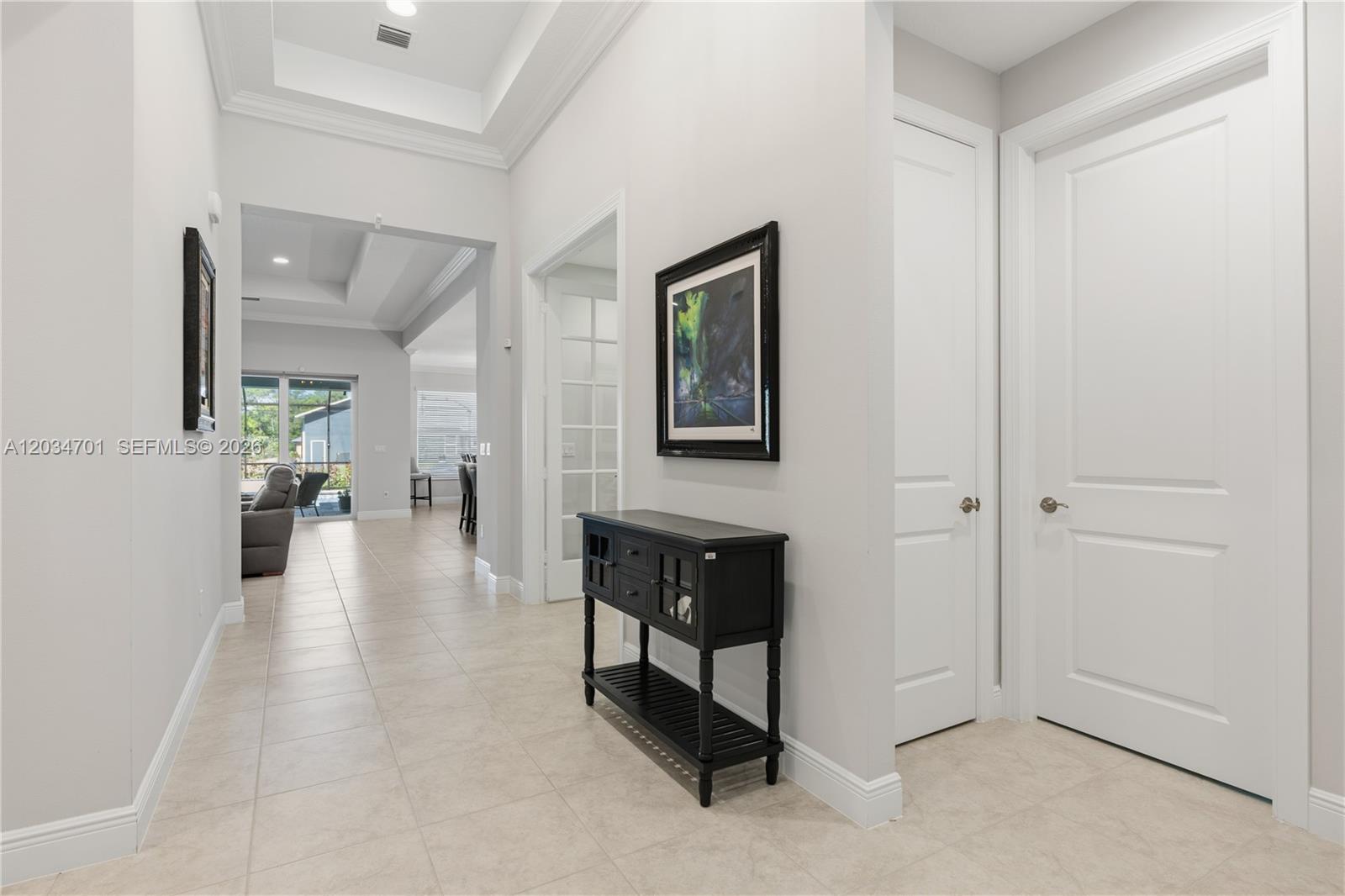 A bright hallway features light tile flooring, white doors, and a black console table — 6805 49th Ct, Vero Beach FL 32967, VERO BEACH, FL