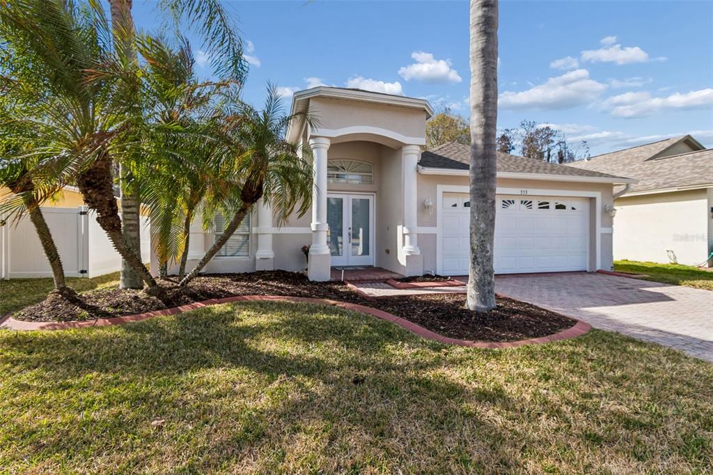 A single-story house with a beige stucco exterior, a two-car garage, and a palm tree — 353 BAY ARBOR, OLDSMAR, FL