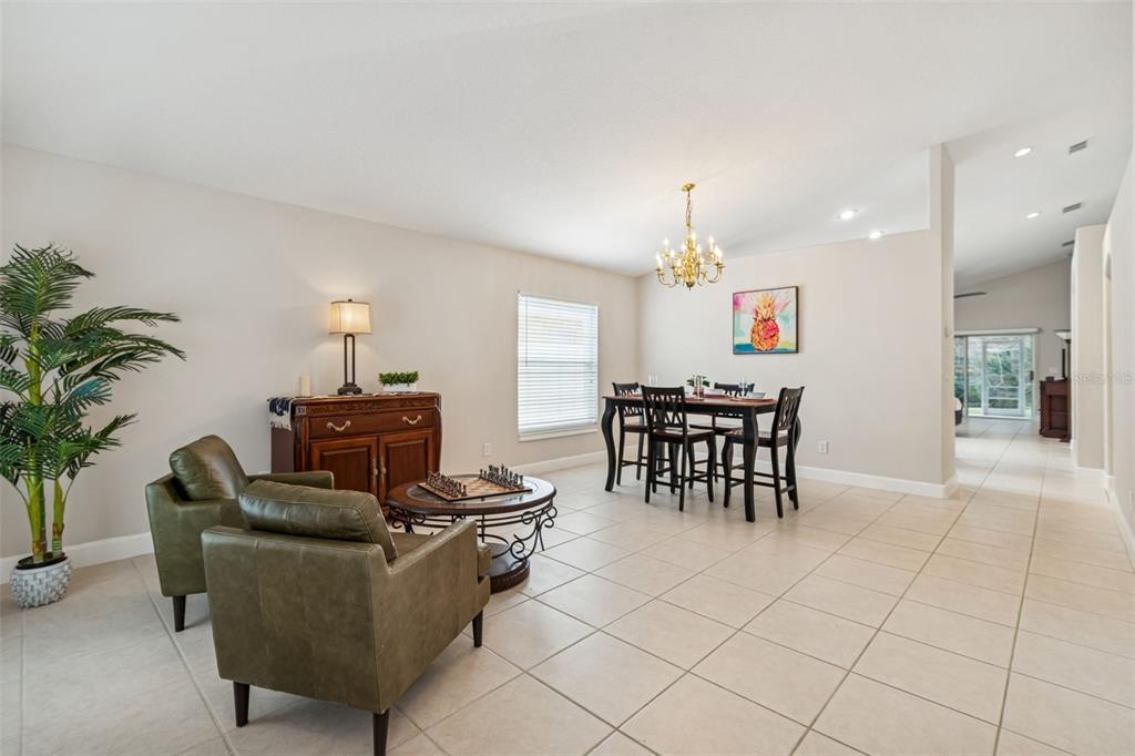 A dining and living area features tile floors, olive green armchairs, and a wooden sideboard — 353 BAY ARBOR, OLDSMAR, FL