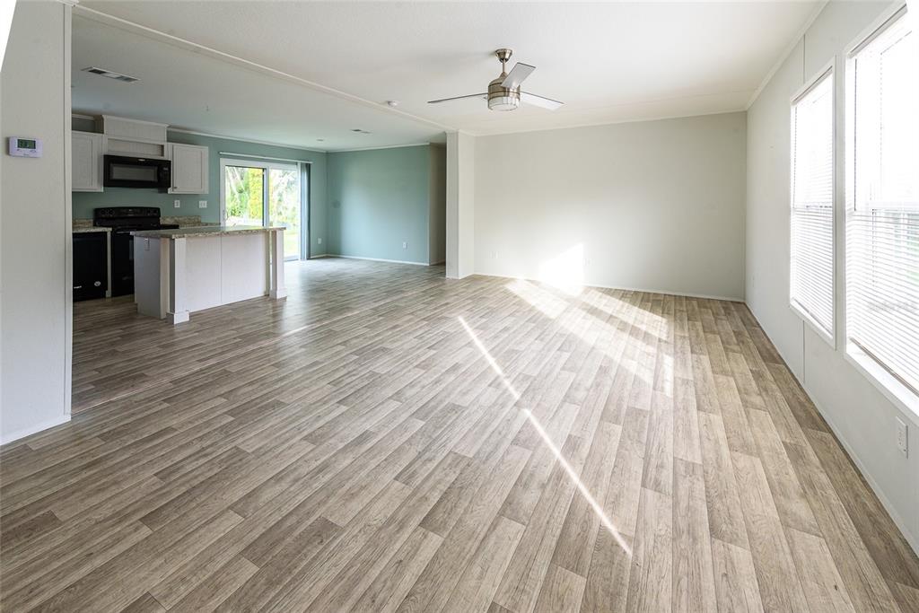 An open-concept living area features wood-look flooring, a ceiling fan, and an adjacent kitchen — 3205 J AND J MANOR ROAD, LAKELAND, FL