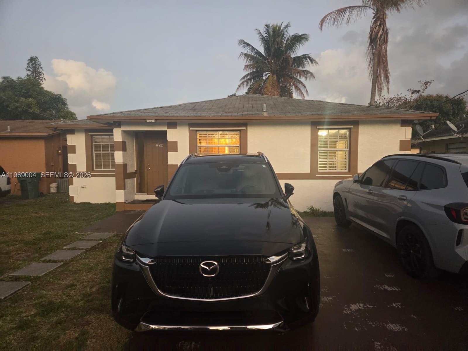 A single-story house with a white facade, brown trim, and two cars parked in front — 230 NW 7th Ave, Dania Beach FL 33004, DANIA BEACH, FL