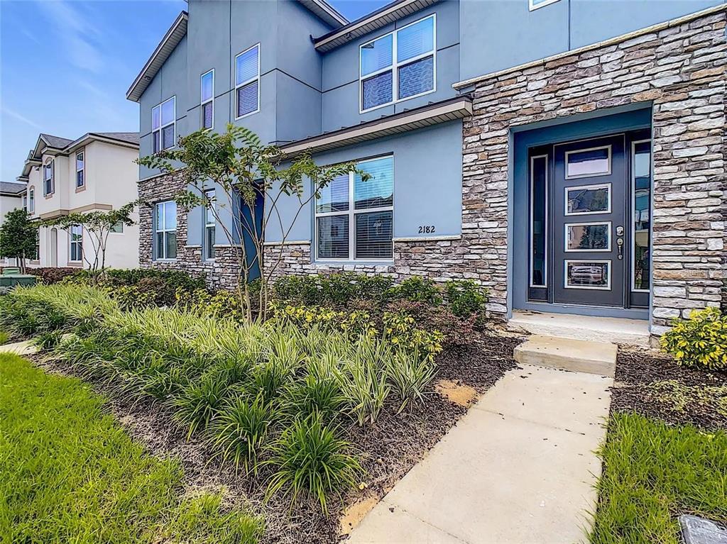 A two-story house exterior features blue siding, stone veneer accents, and a front entrance door — 2182 COOPER BELL PLACE, KISSIMMEE, FL