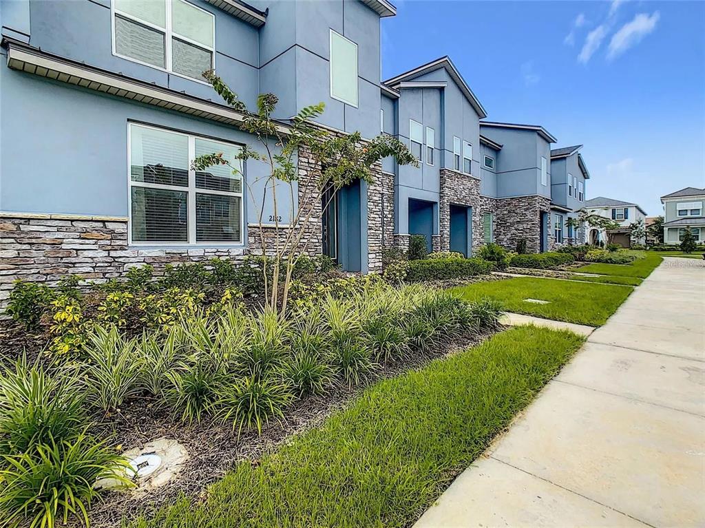 A two-story townhouse exterior with blue siding, stone veneer accents, and a front walkway — 2182 COOPER BELL PLACE, KISSIMMEE, FL