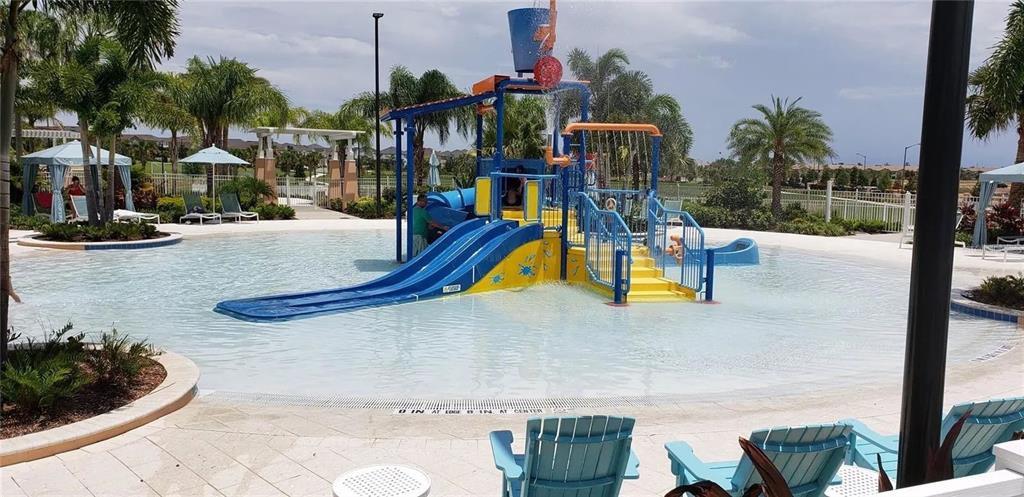 A swimming pool features a blue water slide, a splash pad structure, and lounge chairs — 2182 COOPER BELL PLACE, KISSIMMEE, FL