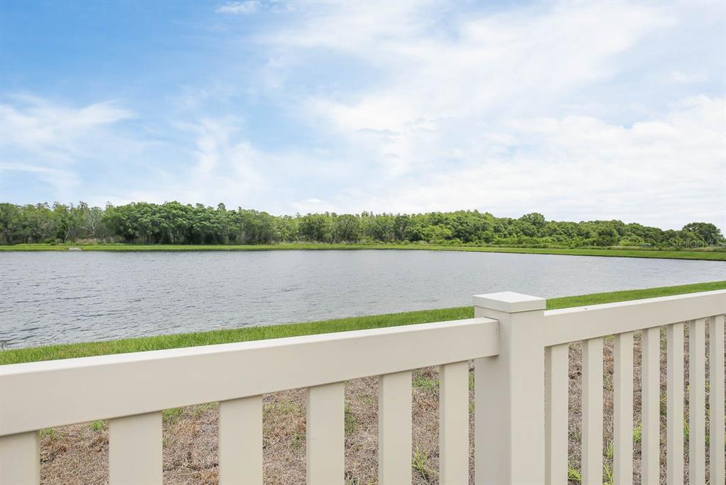 A view of a pond and trees from behind a white vinyl fence — 7322 KING CREEK DRIVE, SUN CITY CENTER, FL