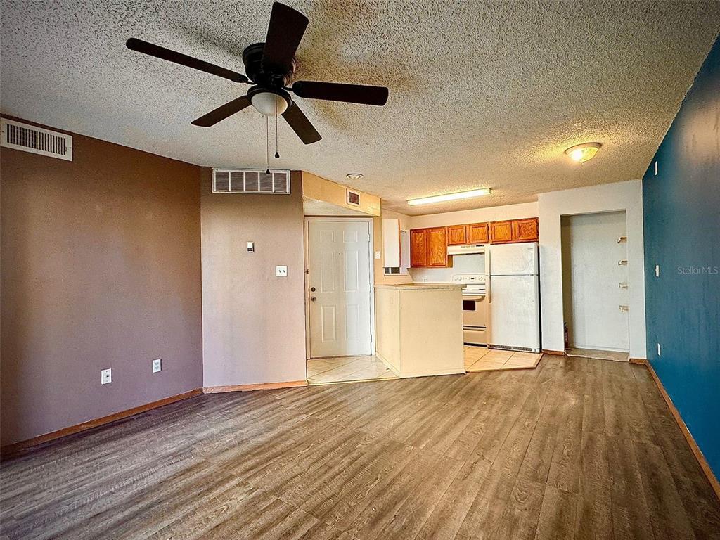 An open-concept living area features wood-look flooring, a ceiling fan, and an adjacent kitchen — 1908 LAKE ATRIUMS CIRCLE UNIT 14, ORLANDO, FL
